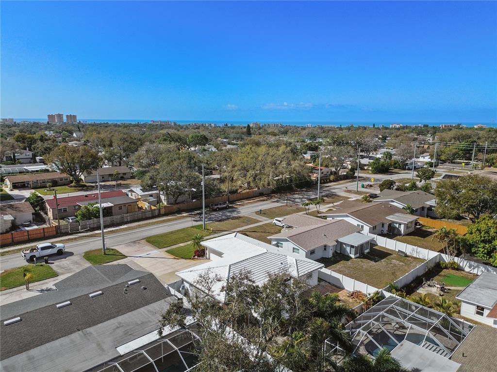 An aerial view shows a residential neighborhood with houses, streets, and a distant coastline — 13565 86TH AVENUE, SEMINOLE, FL