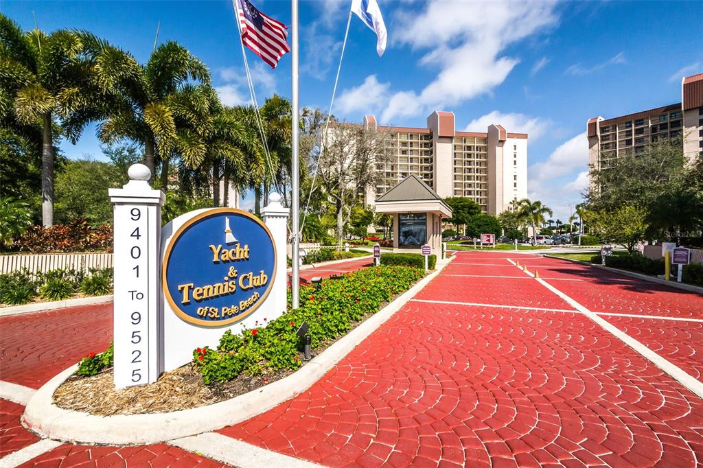 A balcony features a small wooden table and two chairs overlooking a tropical waterfront view — 9495 BLIND PASS ROAD UNIT 205, ST PETE BEACH, FL