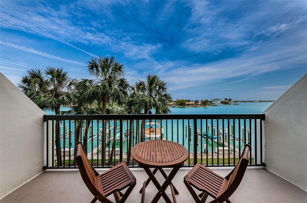 An aerial view shows a waterfront condominium complex with a pool, tennis courts, and boat slips — 9495 BLIND PASS ROAD UNIT 205, ST PETE BEACH, FL