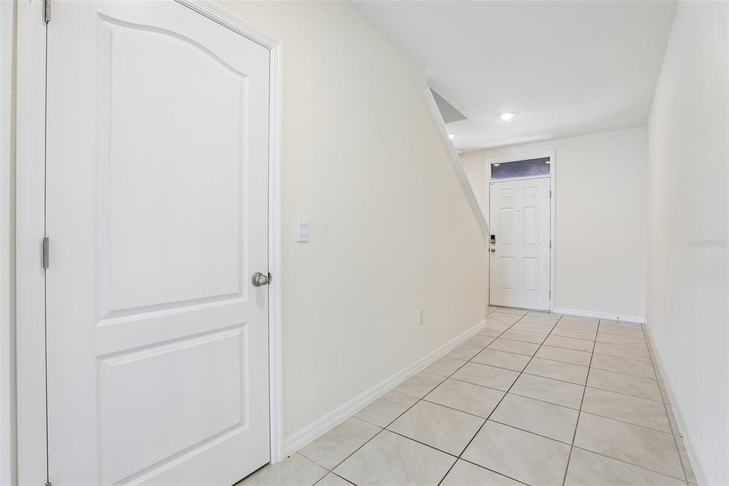 A white door stands in a tiled entryway leading to a front door and stairs — 2945 ELIO HAMMOCK DR, HARMONY, FL