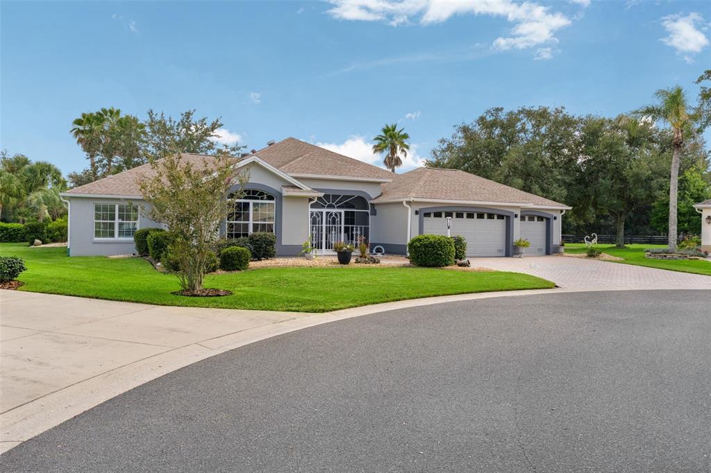 A single-story house with a gray exterior, a shingled roof, and a three-car garage — 1555 COPE PLACE, THE VILLAGES, FL
