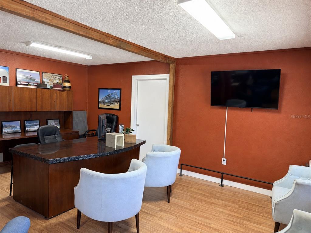 An office with a dark wood desk, light blue chairs, and orange walls — 1005 NW 19TH AVENUE, CHIEFLAND, FL