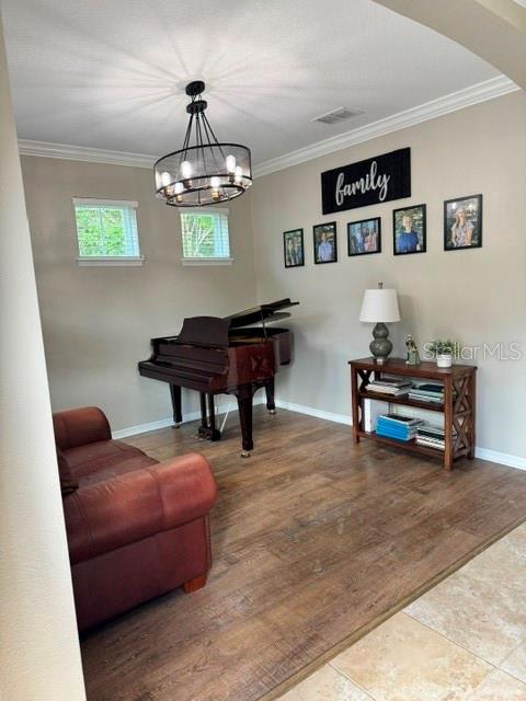 A room with wood-look flooring, a grand piano, a leather sofa, and a chandelier — 8221 NECTAR RIDGE COURT, ODESSA, FL