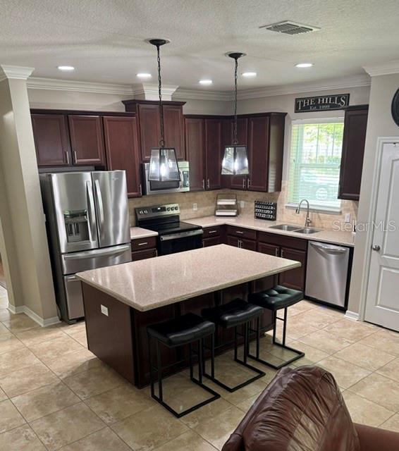 A kitchen features dark wood cabinets, stainless steel appliances, a granite island, and tile flooring — 8221 NECTAR RIDGE COURT, ODESSA, FL