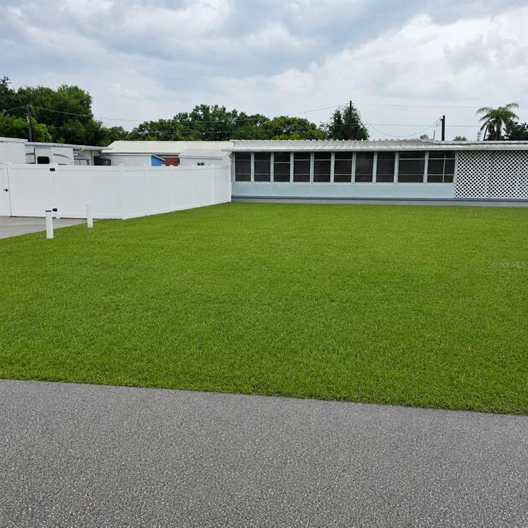 A wide, manicured green lawn sits in front of a mobile home with a screened porch — 2010 OAK STREET, ST CLOUD, FL