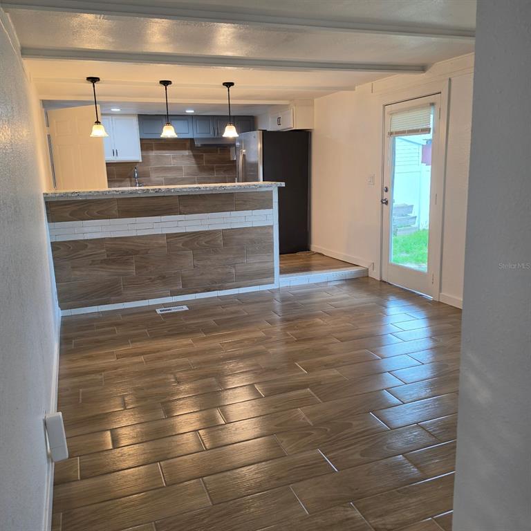 A kitchen with a wood-look tile floor, breakfast bar, and stainless steel refrigerator — 2010 OAK STREET, ST CLOUD, FL