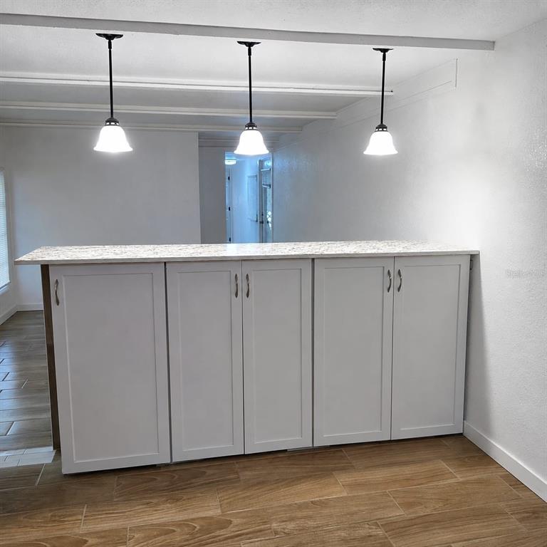 A kitchen island with white cabinets and a speckled countertop sits under three pendant lights — 2010 OAK STREET, ST CLOUD, FL