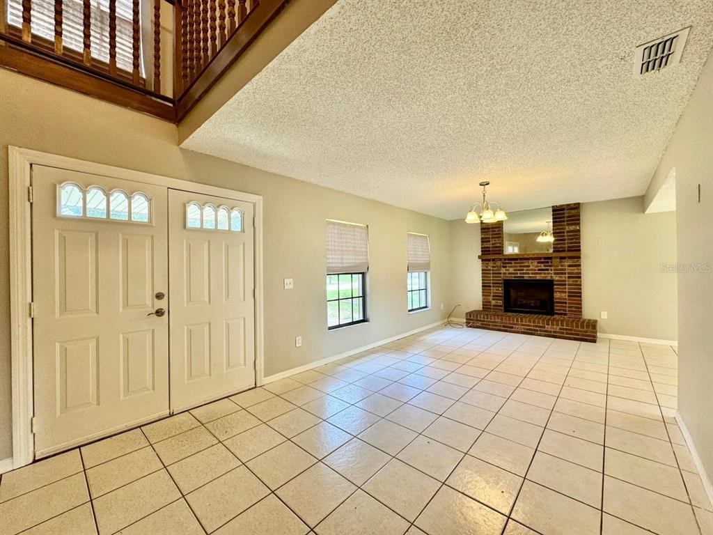 A tiled entryway leads into a living room featuring a brick fireplace and vaulted ceiling — 5132 CHILKOOT STREET, TAMPA, FL