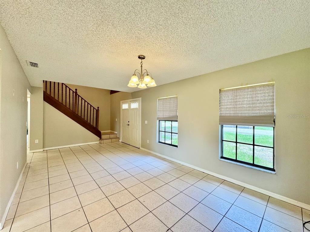 A living room features light tile flooring, a staircase with wooden railings, and two windows — 5132 CHILKOOT STREET, TAMPA, FL