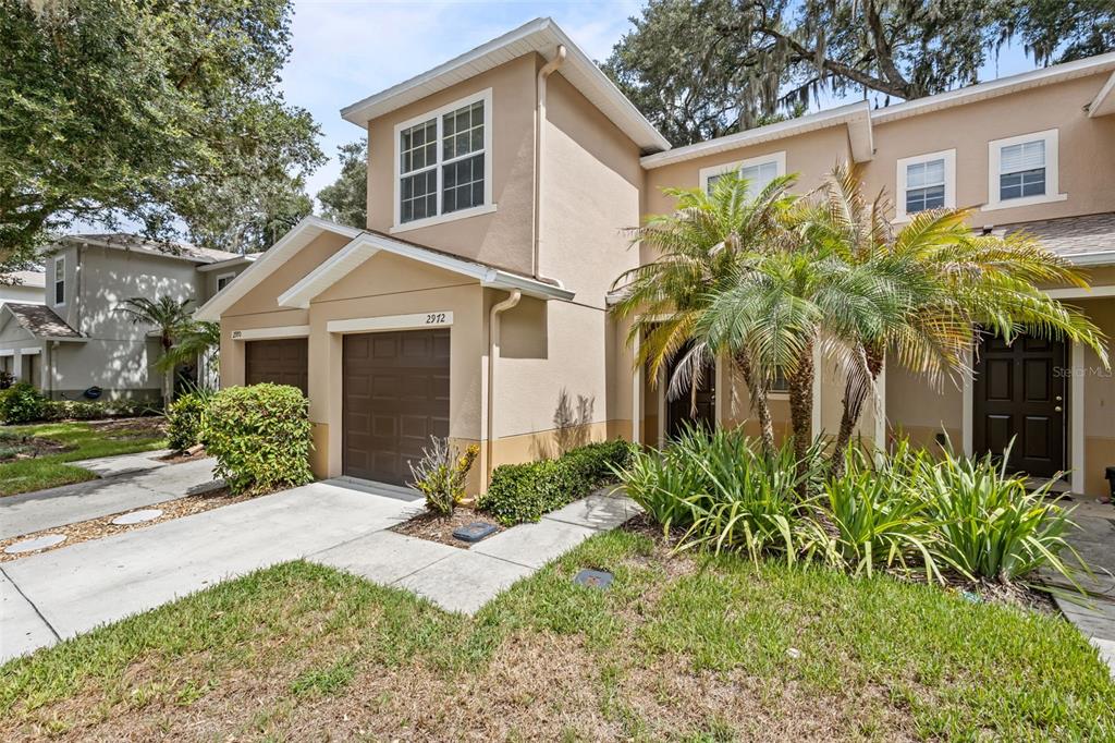 A two-story tan townhouse with brown garage doors and a concrete driveway — 2972 ROYAL TUSCAN LANE, VALRICO, FL