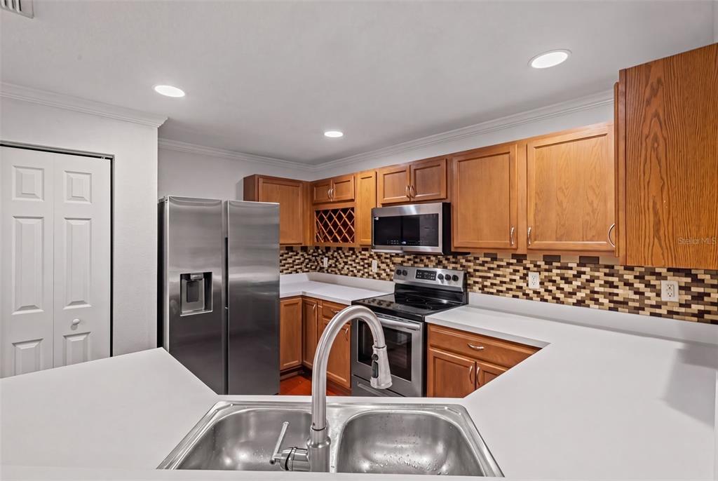 A kitchen with wood cabinets and a breakfast bar overlooks a dining area with flooring — 2972 ROYAL TUSCAN LANE, VALRICO, FL