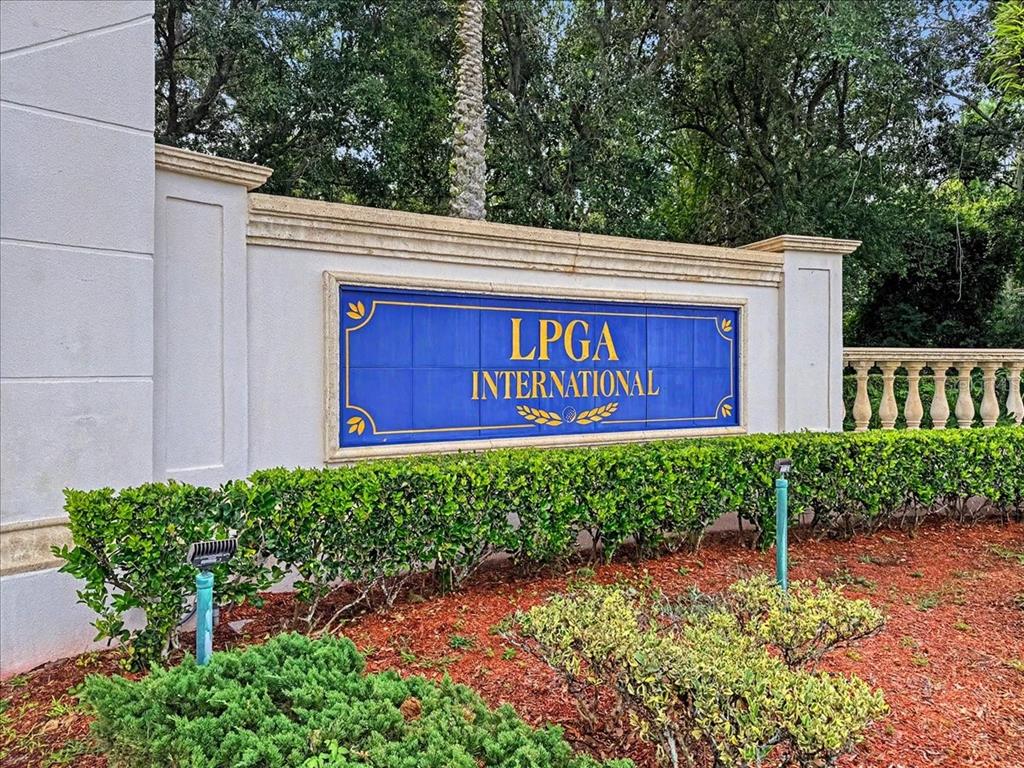 A blue and gold sign for LPGA International sits on a white wall behind hedges — 3149 LEGENDS PRESERVE DRIVE, DAYTONA BEACH, FL