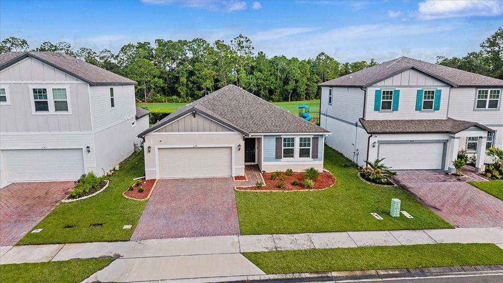 An aerial view shows three suburban houses with brick driveways and manicured lawns — 3149 LEGENDS PRESERVE DRIVE, DAYTONA BEACH, FL