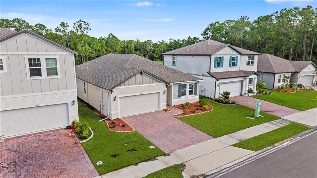 An aerial view shows three suburban houses with paved driveways and manicured lawns — 3149 LEGENDS PRESERVE DRIVE, DAYTONA BEACH, FL