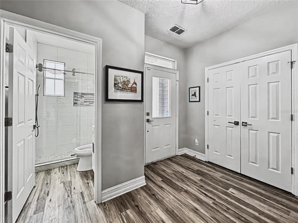 A hallway with wood-look flooring leads to a bathroom with a glass-enclosed shower — 839 LAKE EVALYN DRIVE, CELEBRATION, FL