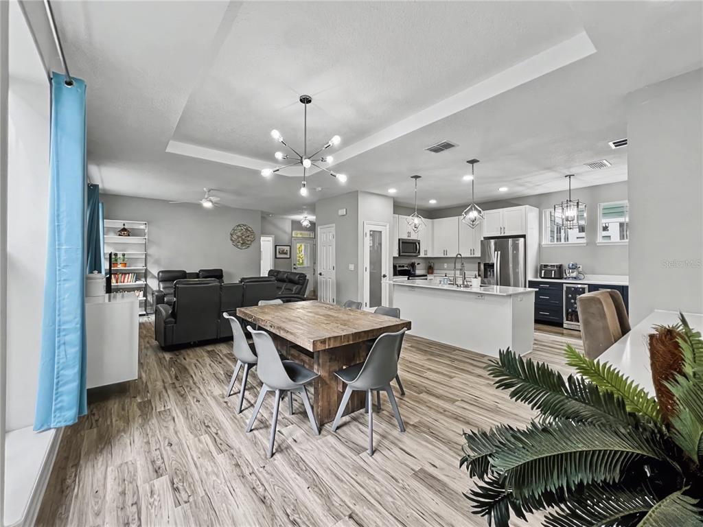 An open-concept kitchen, dining area, and living room feature wood-look flooring and white cabinetry — 839 LAKE EVALYN DRIVE, CELEBRATION, FL