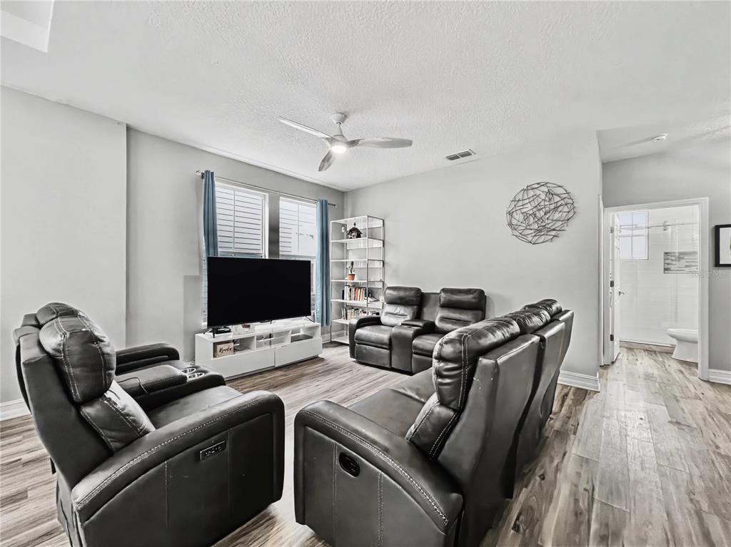 A living room features gray leather recliners, a television on a white stand, and flooring — 839 LAKE EVALYN DRIVE, CELEBRATION, FL