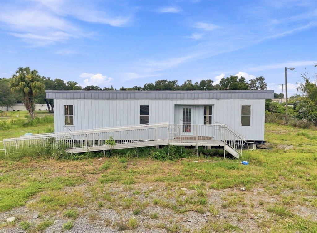 A single-story manufactured home with a metal wheelchair ramp and light gray vertical siding — 4946 E HILLSBOROUGH AVENUE, TAMPA, FL
