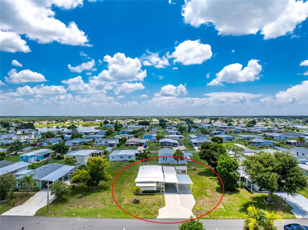 An aerial view shows a single-story house with a carport and driveway in a neighborhood — 1515 SANDERLING DRIVE, ENGLEWOOD, FL