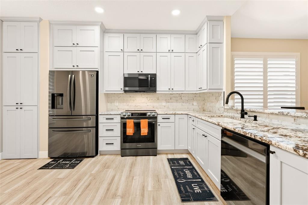 A modern kitchen features light gray cabinets, stainless steel appliances, and a granite countertop — 842 W SILVER MEADOW LOOP, HERNANDO, FL