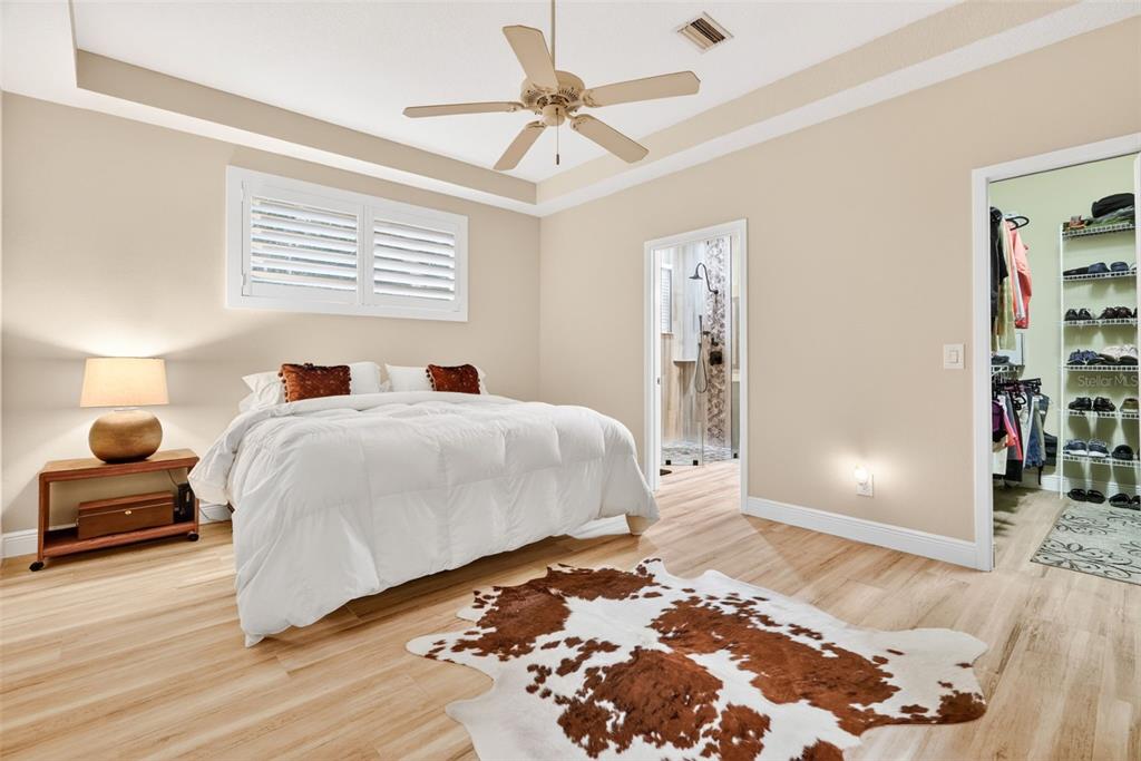 A bedroom with light wood flooring, a white bed, a ceiling fan, and a walk-in closet — 842 W SILVER MEADOW LOOP, HERNANDO, FL