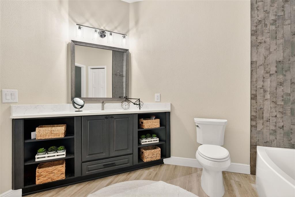 A bathroom features a dark gray vanity with open shelving, a white countertop, and toilet — 842 W SILVER MEADOW LOOP, HERNANDO, FL