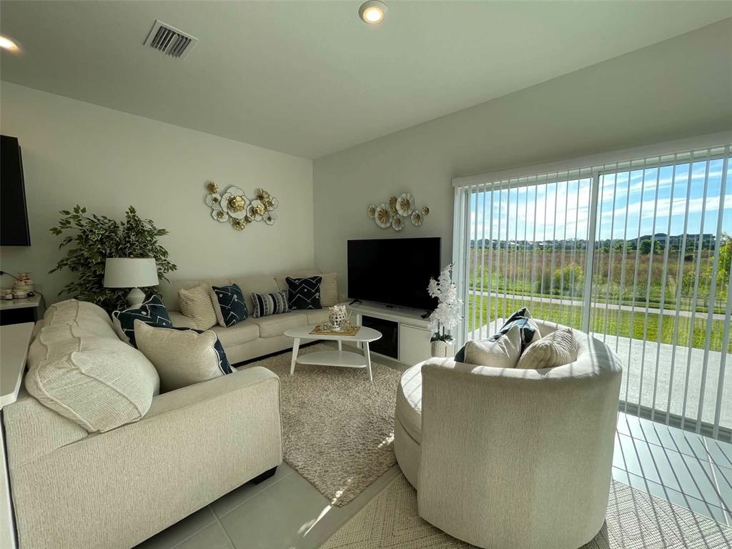 A living room features a beige sectional sofa, a round coffee table, and a sliding door — 2516 PARAVANE WAY, WESLEY CHAPEL, FL