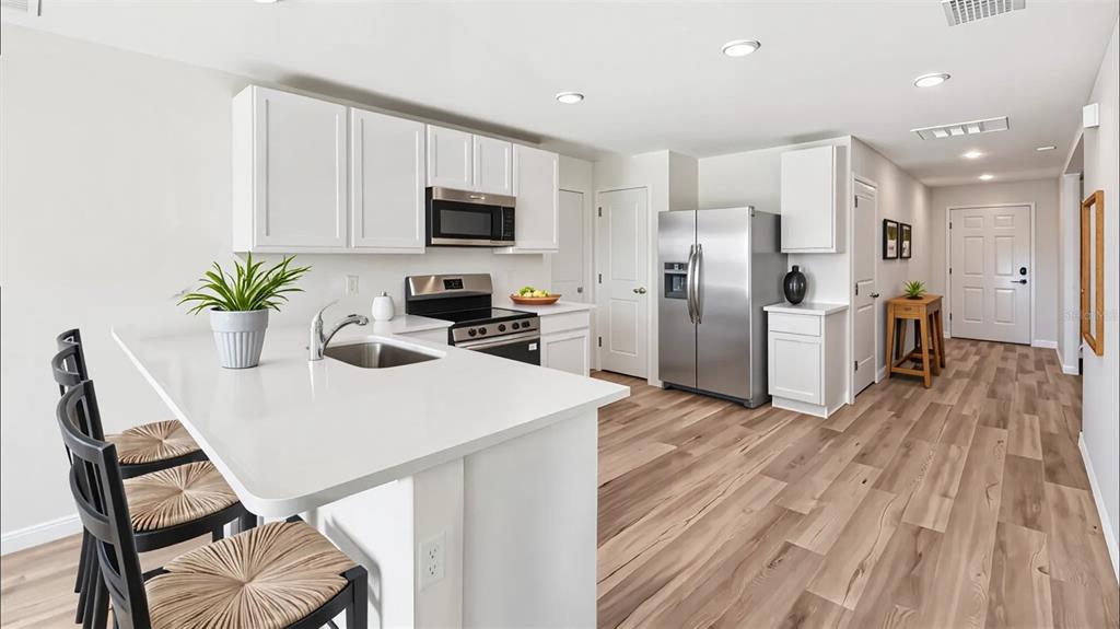 A modern kitchen features white cabinetry, stainless steel appliances, and a central island with seating — 9715 N MITCHELLE DRIVE, DUNNELLON, FL