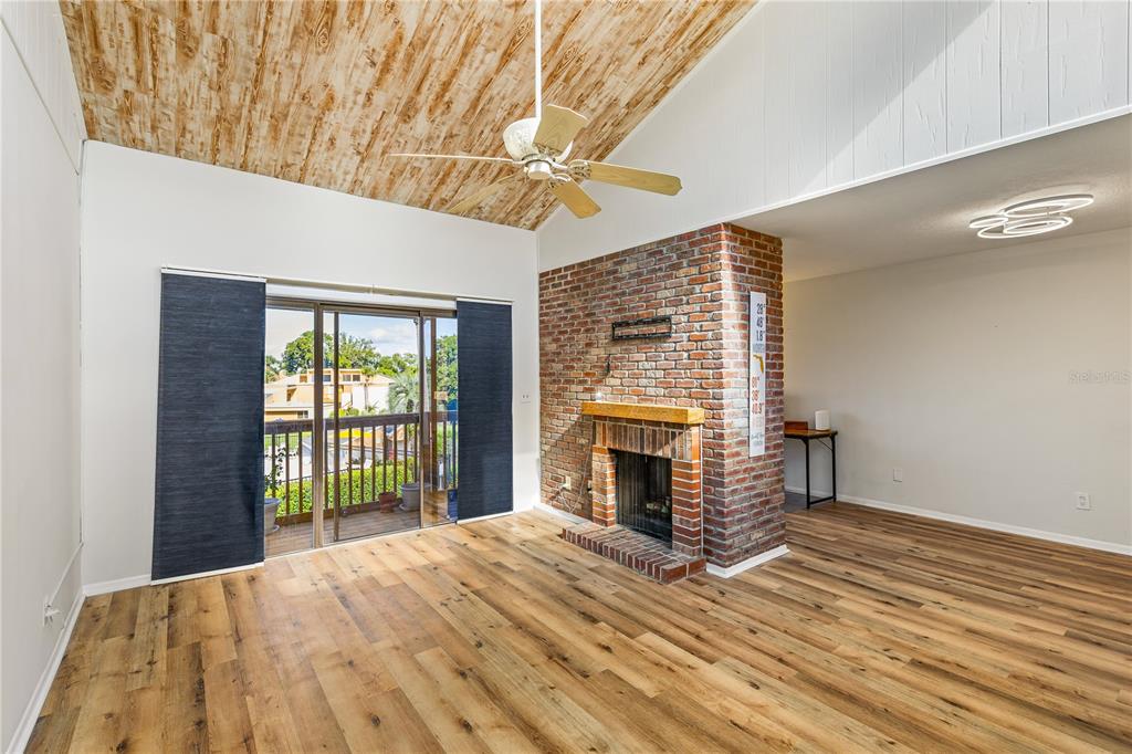 A bright living room with high ceilings, white walls, wicker furniture, and an open kitchen — 1051 S HIGHLAND STREET UNIT 7D, MOUNT DORA, FL
