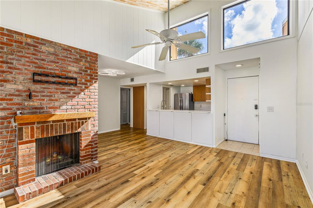 A living room features a vaulted wood-paneled ceiling, white sofa, wicker chairs, and sliding doors — 1051 S HIGHLAND STREET UNIT 7D, MOUNT DORA, FL