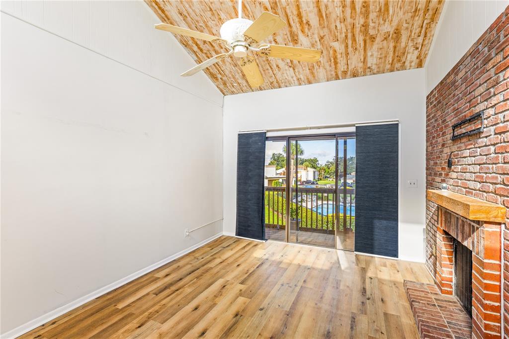 A galley kitchen features light wood cabinets, stainless steel appliances, and white marble-look flooring — 1051 S HIGHLAND STREET UNIT 7D, MOUNT DORA, FL