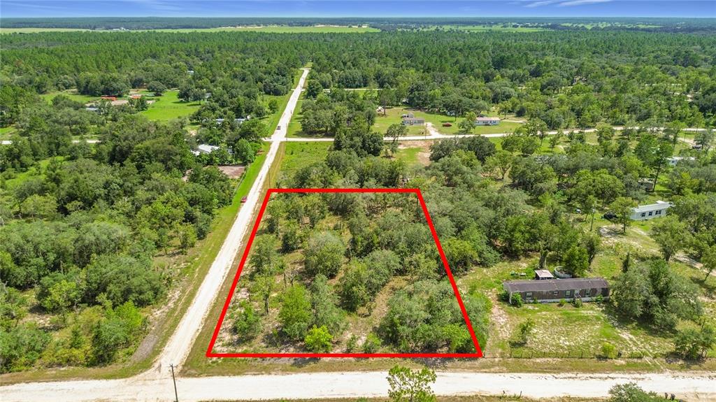 An aerial view shows a rectangular, tree-covered vacant lot outlined in red next to roads — 0 SE 68TH TERRACE, MORRISTON, FL
