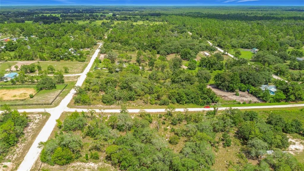 An aerial view shows a rural landscape with dirt roads, scattered trees, and residential properties — 0 SE 68TH TERRACE, MORRISTON, FL