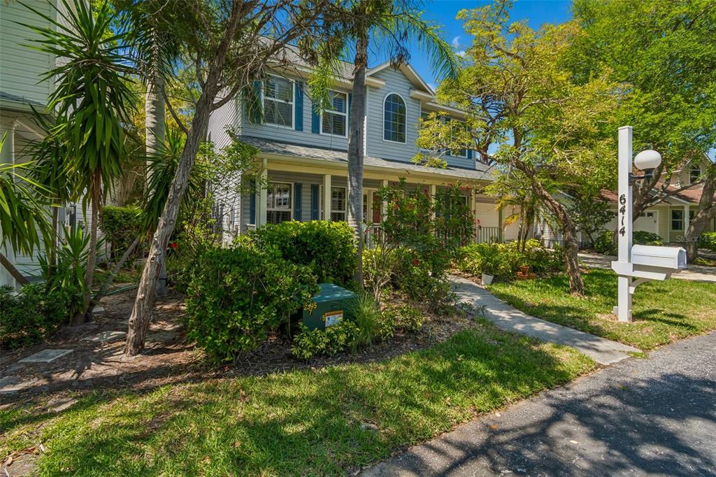 A covered porch features wicker furniture, a small table, and potted plants on brick flooring — 6414 23RD AVE DR W, BRADENTON, FL