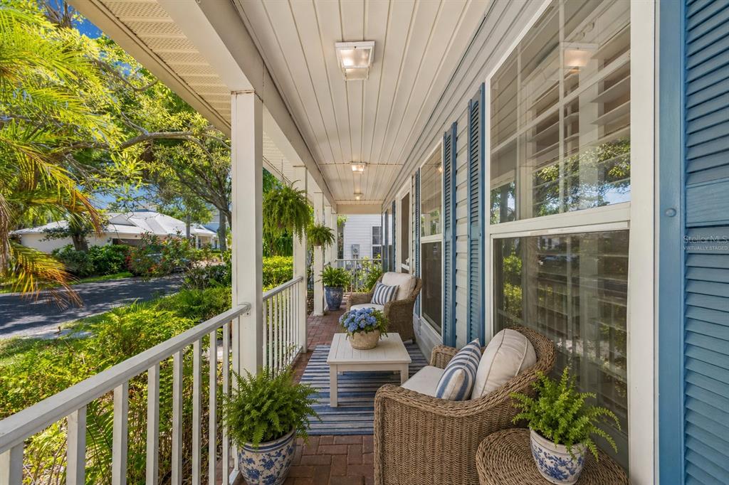 A covered porch with a brick floor, white railings, and blue shutters on the house exterior — 6414 23RD AVE DR W, BRADENTON, FL