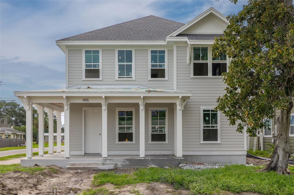 A two-story house with light gray siding, a front porch, and a large magnolia tree — 995 48TH AVENUE N, ST PETERSBURG, FL