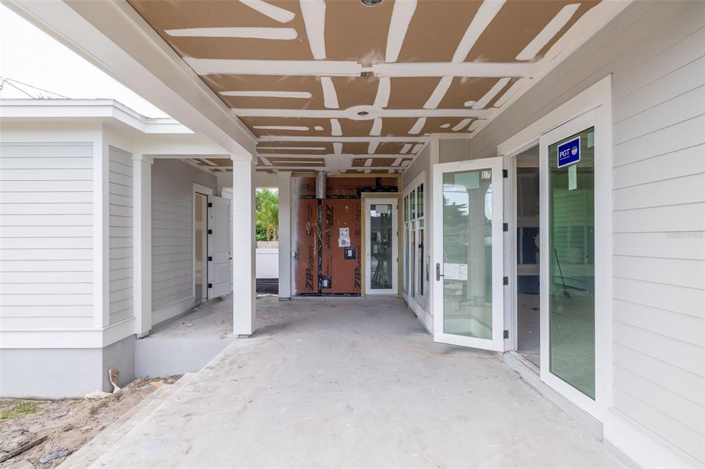 An unfinished covered patio features a concrete floor, exposed ceiling panels, and glass sliding doors — 995 48TH AVENUE N, ST PETERSBURG, FL