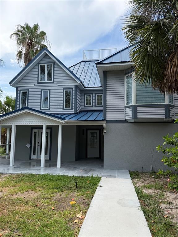 A two-story house with gray siding, a blue metal roof, and a covered front porch — 887 S GULFVIEW BOULEVARD, CLEARWATER BEACH, FL