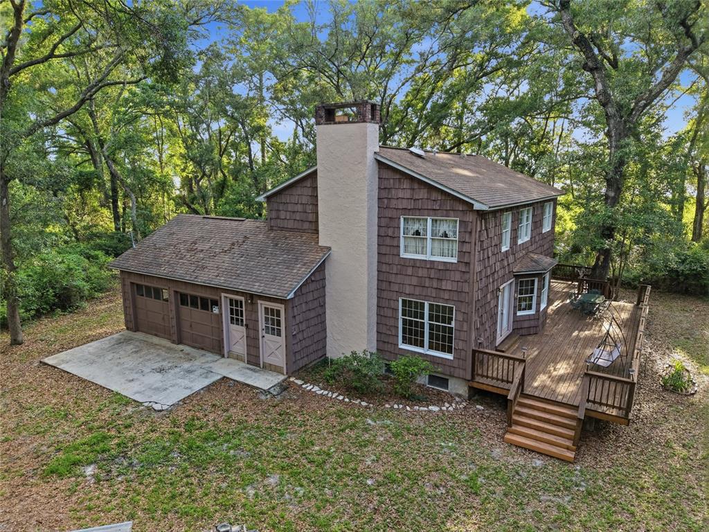 An aerial view shows a two-story brick house nestled within a dense forest — 9291 NW 127TH PLACE, CHIEFLAND, FL