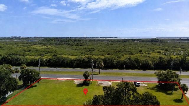 An aerial view shows a vacant, rectangular grassy lot bordered by a road and vegetation — 2606 N DIXIE FREEWAY, NEW SMYRNA BEACH, FL