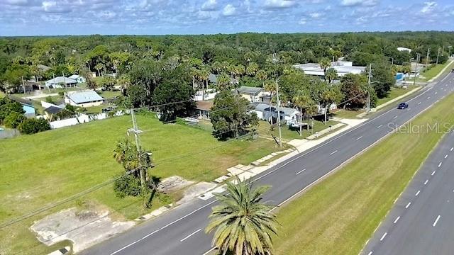 An aerial view shows a grassy lot adjacent to a multi-lane road and nearby houses — 2606 N DIXIE FREEWAY, NEW SMYRNA BEACH, FL
