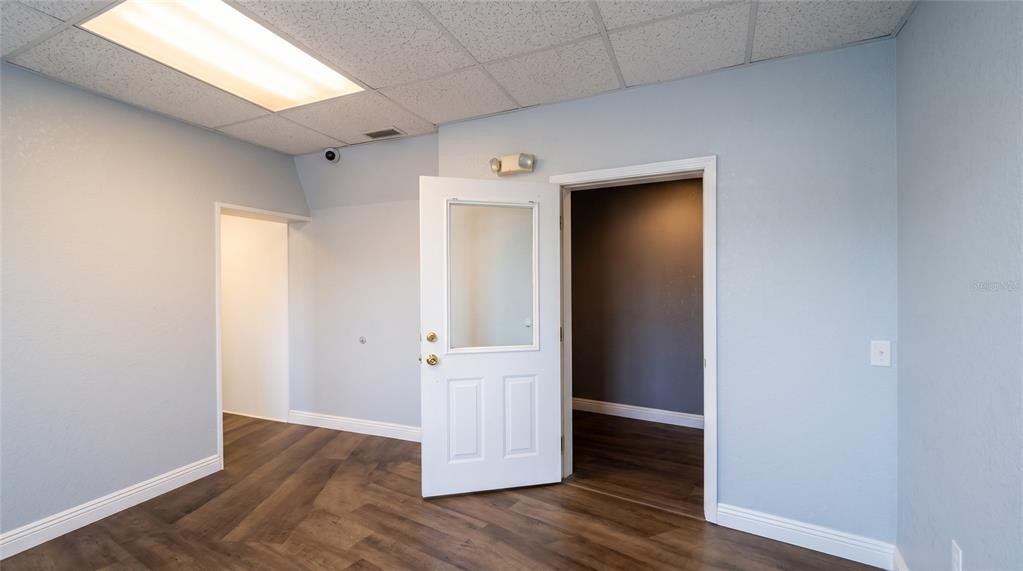 A hallway with wood-look flooring leads toward a doorway under a drop ceiling — 223 N COMMONWEALTH AVENUE SW, POLK CITY, FL