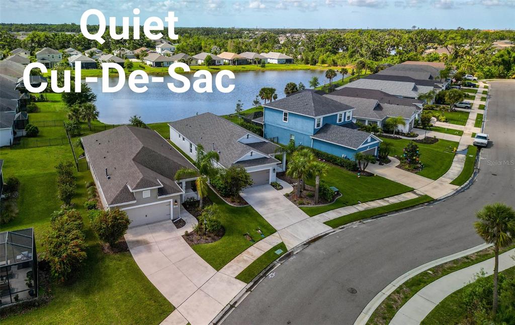 An aerial view shows suburban houses with driveways situated along a curved street near a lake — 4815 DEEP CREEK TERRACE, PARRISH, FL