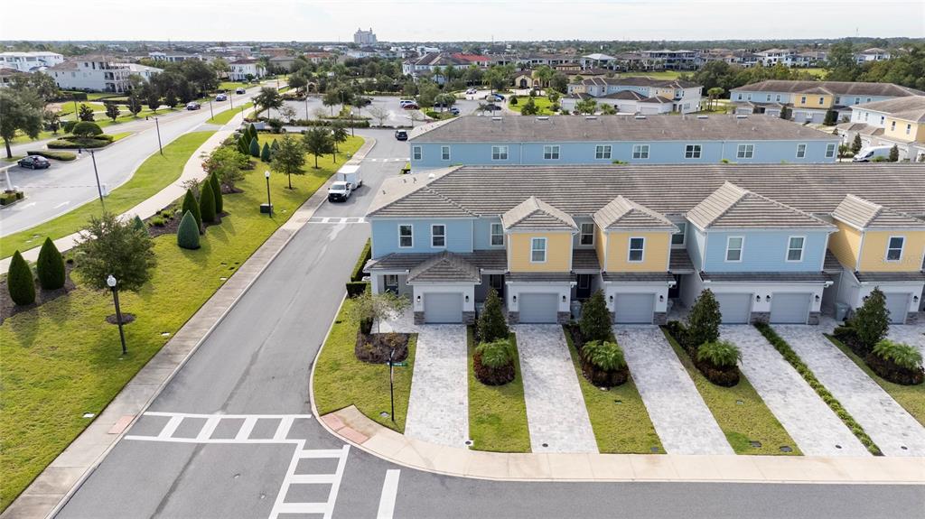 An aerial view shows a row of multi-story townhomes with garages and paved driveways — 7900 DRAW STREET, REUNION, FL