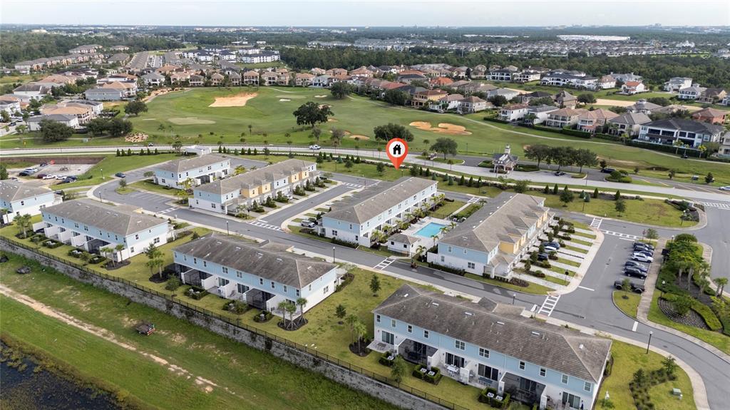 An aerial view shows multiple multi-story townhomes with a swimming pool and a golf course — 7900 DRAW STREET, REUNION, FL