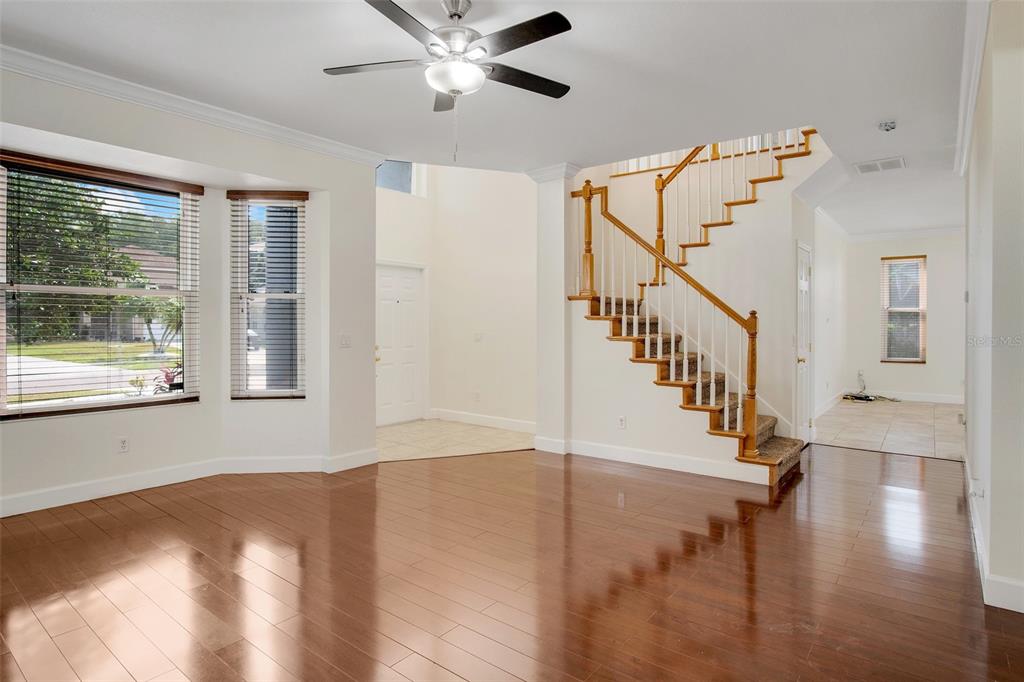 An empty living room features hardwood floors, white walls, and two ceiling fans — 12661 ENCLAVE DRIVE, ORLANDO, FL