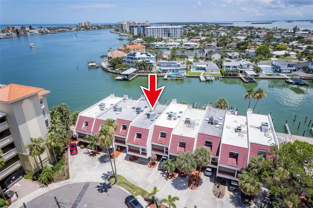 An aerial view shows a row of waterfront townhomes with red-tiled roofs and boat docks — 218 SKIFF POINT, CLEARWATER BEACH, FL