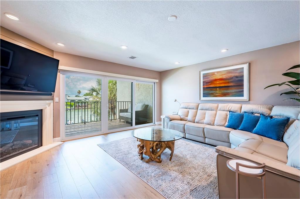 A living room features a fireplace, a sectional sofa, a glass coffee table, and balcony access — 218 SKIFF POINT, CLEARWATER BEACH, FL