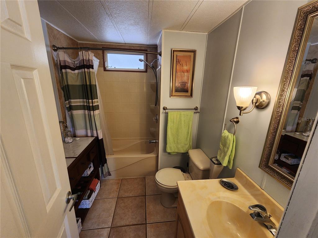 A bathroom features a vanity, a toilet, and a shower-tub combination with a tiled floor — 808 53RD AVENUE E UNIT 27, BRADENTON, FL