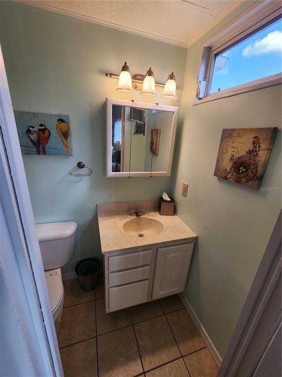 A small bathroom features a vanity with a beige countertop, a medicine cabinet, and toilet — 808 53RD AVENUE E UNIT 27, BRADENTON, FL